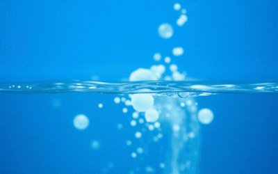 A tiszta folyó víz közeli felvétele, alatta lágyan ragyogó absztrakt formákkal, egy tiszta kék háttér előtt, amely a tisztaságot és az egészséget s...